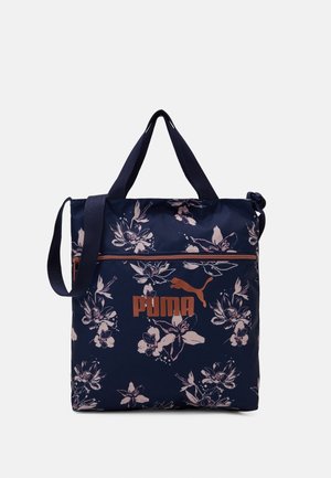 Navyblauwe Puma-tas met bloemenprint, voorzien van dubbele handvatten, verstelbare schouderriem en een voorvak met rits.