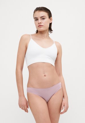 Hvit ribbestrikket bralette med tynne stropper, kombinert med lyserosa sømløse bikinibukser. Glatt tekstur, enkel design. Ingen synlige mønstre eller dekorasjoner.