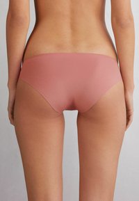 Roz roze naadloze bikini slip met een lage taille en een gladde textuur, met minimale bedekking en geen zichtbare hardware.