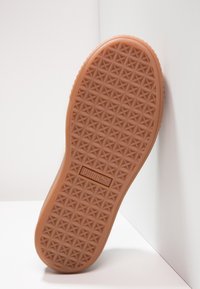 Gumová podešev v tan barvě s texturovaným vzorem malých hvězdiček a logem PUMA v obdélníkové oblasti poblíž paty.