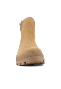 Bocanci scurți din suede bej, cu talpă din cauciuc, vârf rotund și mânere de prindere. Talpa dispune de un model texturat pentru aderență.