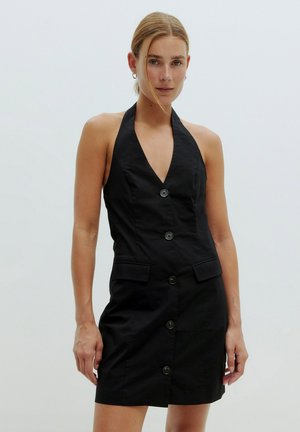 Zwarte halterjurk met een diepe V-hals, voor knoopsluiting en zijzakken. De stof is glad met een getailleerd silhouet.