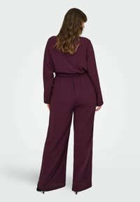 Bordeaux jumpsuit van zachte stof, met lange mouwen, een elastische tailleband en wijde pijpen met subtiele glinsteraccenten.