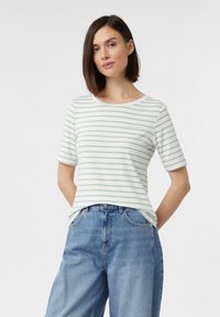 Pasiasta koszulka z krótkim rękawem w jasnoniebieskim i białym kolorze, z okrągłym dekoltem i miękkiego materiału, w połączeniu z dżinsami o wysokim stanie.