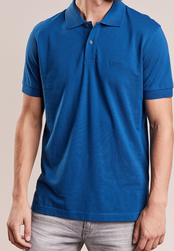 Polo bleu en coton avec une texture côtelée. Il comporte une patte de boutonnage à trois boutons et un petit logo embossé sur la poitrine.