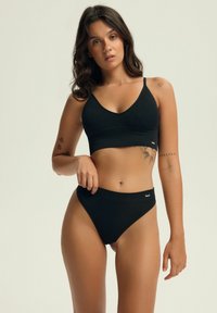 Czarny zestaw bikini z prążkowanej tkaniny, z biustonoszem w kształcie v z regulowanymi ramiączkami oraz wysokimi majtkami, oba z dyskretnym logo.