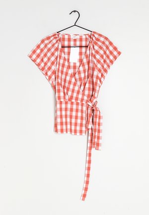 Rød og hvid gingham-wrap-bluse med korte ærmer og bindebånd i taljen, hængende på en sort bøjle mod en hvid baggrund.