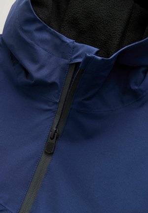 Navy blue jacket featuring a soft black fleece lining, high collar, and a contrasting zipper with textured pull tab. Smooth outer material.