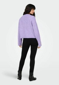 Pull court violet clair, à manches longues et finition texturée, assorti à un pantalon noir ajusté et des bottines. 