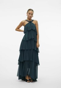Duga, tamnozelena chiffon haljina s višeslojnim volanima, halter vratom s čvorom, koja pada do dužine do poda.