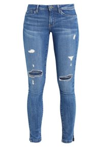 Jeans ajustados de denim azul medio desgastado, con áreas desgastadas y desgarros en las rodillas. La tela tiene una textura suave con ligero estiramiento y un diseño clásico de cinco bolsillos.