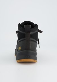 Chaussure haute noire en tissu texturé et matériaux synthétiques. Dispose d'une semelle en caoutchouc et d'un accent de logo jaune sur le côté.