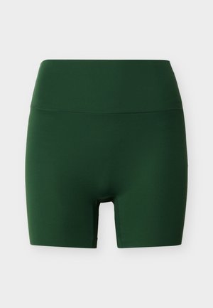 Σκούρα πράσινα αθλητικά σορτς ψηλόμεσα και εφαρμοστά με λεία μέση και μήκος έως το γόνατο, σε ανοιχτό φόντο.