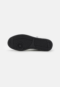 Suola di sneakers nera in gomma con righe testurizzate e accenti circolari. Design durevole con profilo piatto per stabilità.