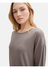 Lange mouwen, losse top in een gedempt taupe kleur. Zachte stof met een ronde halslijn en brede mouwen, minimale stiksels.