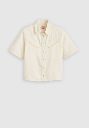 Šviesiai kreminės medvilnės trumpų rankovių marškiniai su mygtukais. Yra dvi krūtinės kišenės su įstrižais atvirais dangteliais, klasikinis apykaklė ir sidabro spalvos snapeliai.