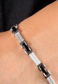 Bracciale in mesh argento con accenti neri rettangolari e connettori metallici, che mette in mostra un design elegante e intrecciato sul polso.