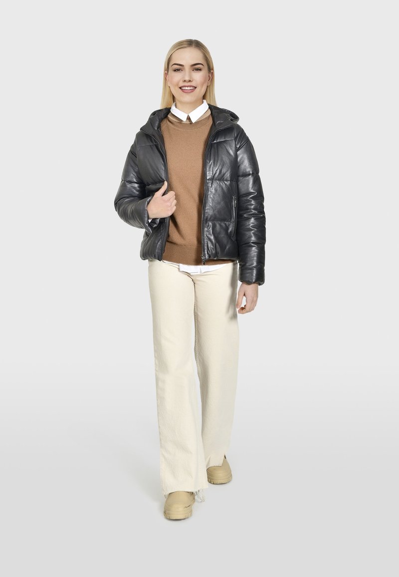 Schwarze Daunenjacke, beiger Pullover, weißes Hemd mit Kragen, cremfarbene weite Hose und beige Sneaker. Glatte Textur, lässiges Design.