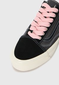 Black and gray sneaker with a suede toe cap, pink laces, and white rubber outsole. Features white stitching and denim-like material.