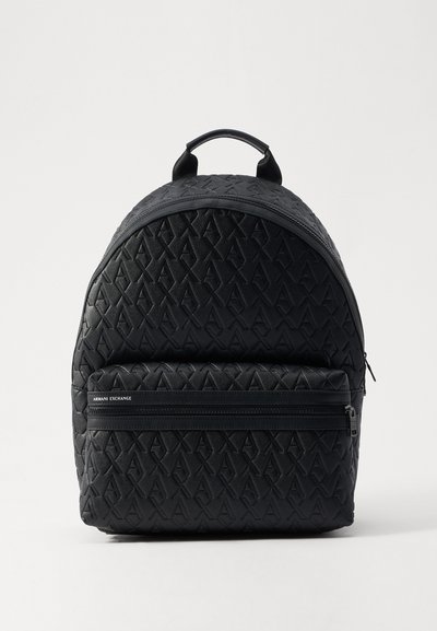 Sac à dos en cuir noir avec motif de logo en relief, forme arrondie, poignée supérieure et poche frontale zippée. Surface texturée avec des accents prononcés.