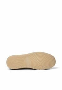 Schuhsohle mit einer glatten, beigen Gummioberfläche, die strukturierte kreisförmige und Zickzack-Muster für Traktion und Grip aufweist.