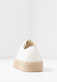 Espadrilla bianca in tela con suola in juta intrecciata, caratterizzata da una tomaia testurizzata e cuciture a contrasto. Tacchetto arrotondato sul retro.
