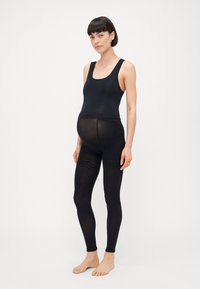 Juodos leggingai su lygiu, tamprių audiniu ir aukštu liemeniu, sukurti patogumui nėštumo metu. Pasižymi minimaliais akcentais.