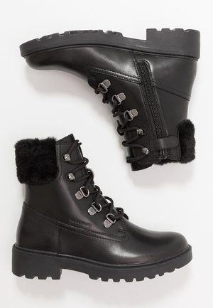 Sorte læderankelstøvler med kunstpelskant, rund snude, metaløjer og tyk gummisål med mønster. Side lynlåsdétail.