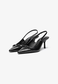 Musta nahkainen slingback-kengät, joissa on terävät varpaat, pienet korot ja koristeellinen varuste etuosassa, sileä pinta.