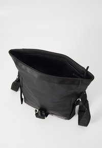 Borsa a tracolla nera realizzata in materiale resistente, con chiusura superiore a zip, tracolla testurizzata e un ampio interno foderato in modo liscio.