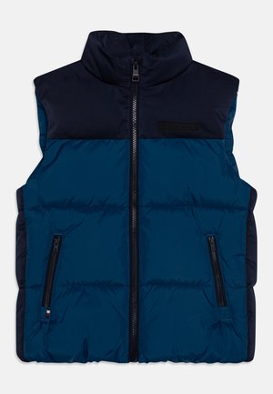 Gilet imbottito senza maniche con blocchi di colore blu navy e blu scuro, collo alto, cerniera frontale e due tasche laterali con zip.