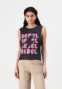 Juodas be rankovių marškinėliai su ryškiu rožiniu tekstu "REBEL" ir žaibo dizainu. Lygi medvilnės medžiaga su laisvu siluetu.