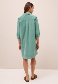 Abito verde menta a metà coscia con colletto, maniche a tre quarti e uno spacco nella schiena. Tessuto morbido con un design casual.