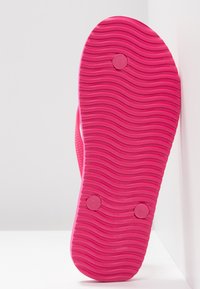Pink rubber flip-flop sole featuring a textured wavy pattern, labeled with 'S' and 'L' near the heel. Smooth edges emphasize the design.
