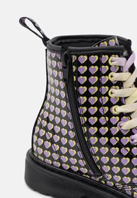 Černé kotníkové boty s lesklým povrchem, zdobené vzorem fialových a žlutých srdcí. Mají boční zip a smetanové tkaničky. Texturovaná podrážka.