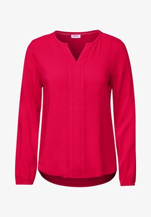 Blouse rouge à manches longues avec un col en V, présentant une surface texturée et des poignets froncés. Ourlet droit avec une légère courbe à l'arrière.