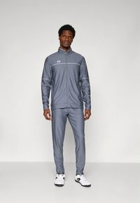 Grauer sportlicher Trainingsanzug mit Reißverschlussjacke und Hose, ausgestattet mit weißen Akzenten und einem Logo auf der Brust, gefertigt aus glattem, atmungsaktivem Stoff.