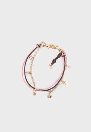 Bracelet délicat avec des cordons roses et marrons, chaîne en or, petits charms en or comprenant étoile, fleur, chaussure et pacman, sur fond blanc.