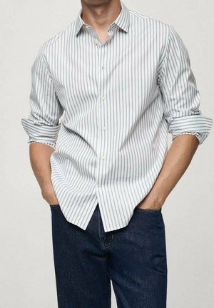 Gestreept overhemd van lichte stof, met verticale blauwe en witte strepen, een kraag en opgerolde mouwen. Draagt men met donkere jeans.