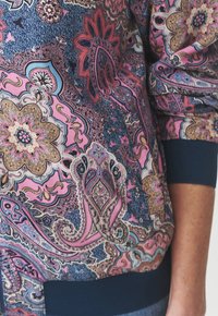 Mustriga bomber-jakk, millel on paisley-muster roosa, mereväe ja kreemika värviga. Mereväe värvi soonikkoesed ja hem. Pehme kangas koos keerukate detailidega.