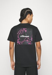 Black cotton t-shirt featuring a colorful abstract graphic design on the back with the text "ellesse" in white at the center.