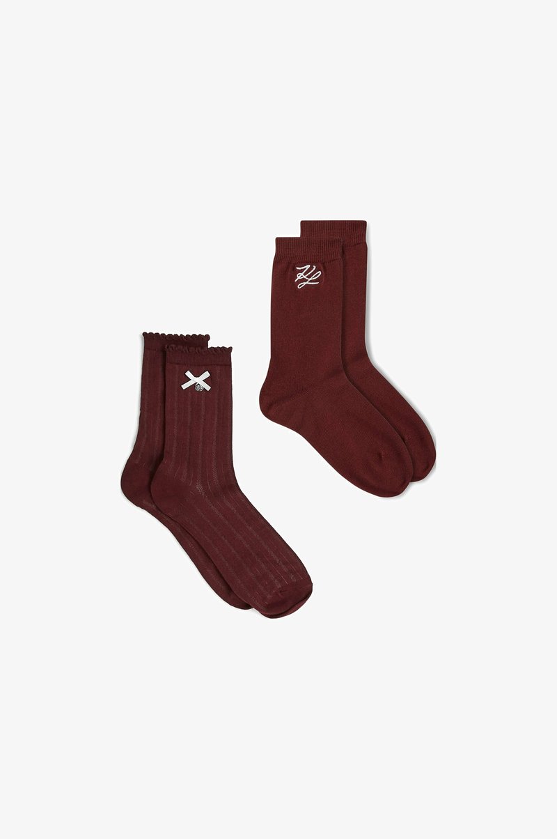 Deux paires de chaussettes bordeaux, l’une avec un motif côtelé et un détail de nœud blanc, l’autre unie avec des initiales brodées blanches.