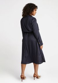 Navy blue striped midi dress with a belted waist, long sleeves, and side slits. Made of smooth fabric, features button accents.