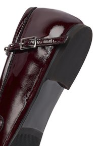 Chaussure en cuir verni bordeaux avec un bout carré, accent de boucle argentée, surface texturée et un petit talon noir robuste.