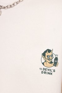 Κρέμα βαμβακερή μπλούζα με γραφική εκτύπωση ενός διαβολικού χαρακτήρα που φορά στρογγυλά γυαλιά ηλίου και κρατά μια μπίρα, με την ένδειξη "ΤΟ ΠΟΤΟ ΤΟΥ ΔΙΑΒΟΛΟΥ."