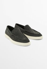 Schwarze Wildlederloafers mit glatter Oberfläche, ausgestattet mit gesteppten Details und einer kontrastierenden, cremefarbenen Gummisohle. Klassisches Schlupfdesign.