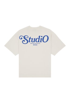 T-shirt beige à manches courtes avec texte bleu « StudiO », « Crafting Aesthetics » et « WRSTBHVR » au dos, présenté à plat sur fond blanc.