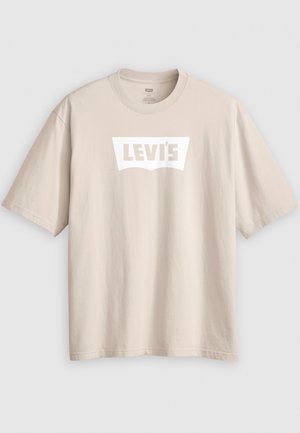 Bež majica kratkih rukava od pamuka, s bijelim logotipom "LEVI'S" klasičnog oblika na prednjoj strani. Jednostavan, neukrašen dizajn.