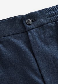 Pantalon en laine bleu foncé avec taille boutonnée et dos élastiqué pour un ajustement réglable.