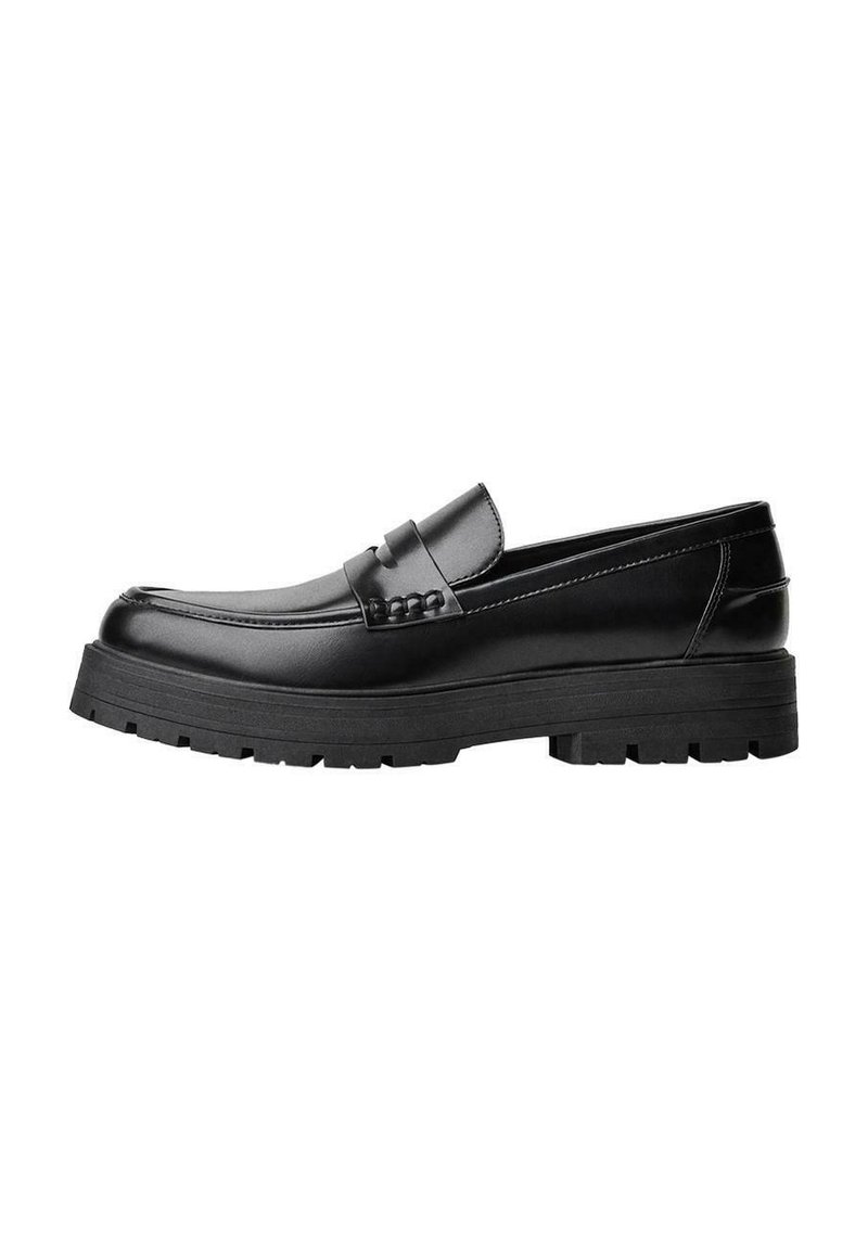 Zwarte leren loafer met een chunky profielzool en een decoratieve band over de bovenkant, weergegeven in het linkerzijprofiel op een witte achtergrond.
